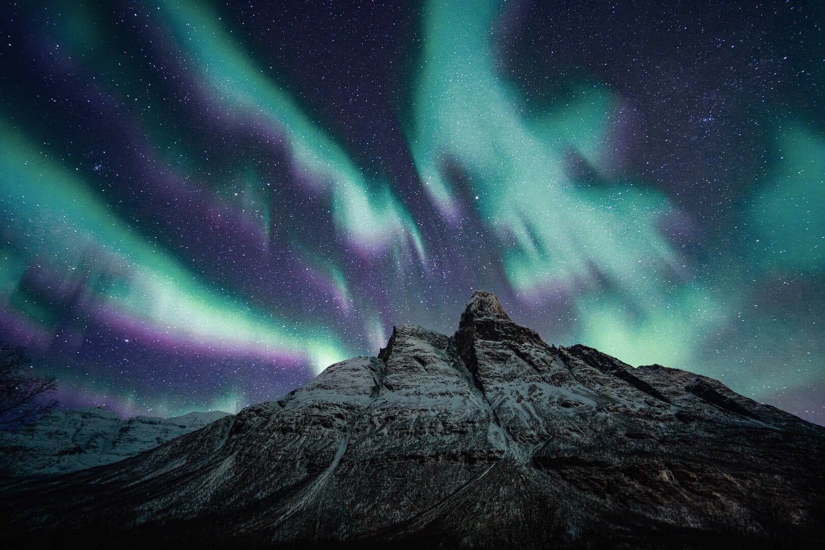 Green and violet aurora over the snow-covered peak of Otertind in Signaldalen, Northern Norway