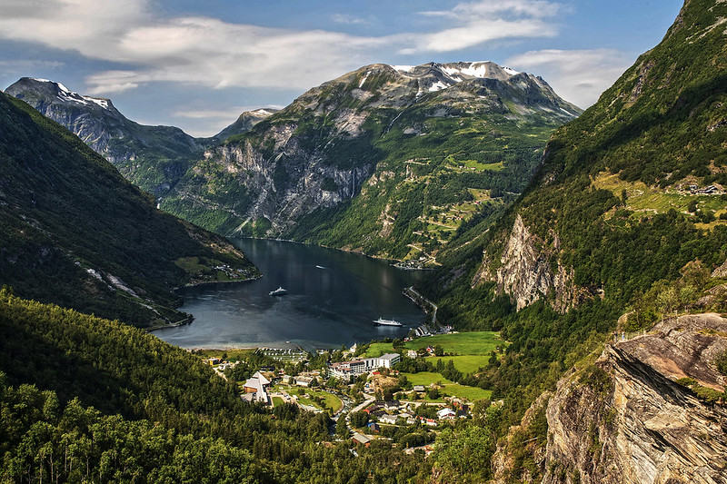 Panoramic view of Geiranger village and Geirangerfjord from an elevated position, mountains rising on both sides of the fjord