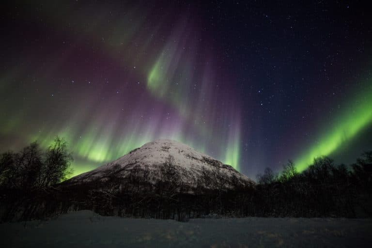 Green and violet aurora over a snow-covered peak in Tamokdalen, inland from Tromsø