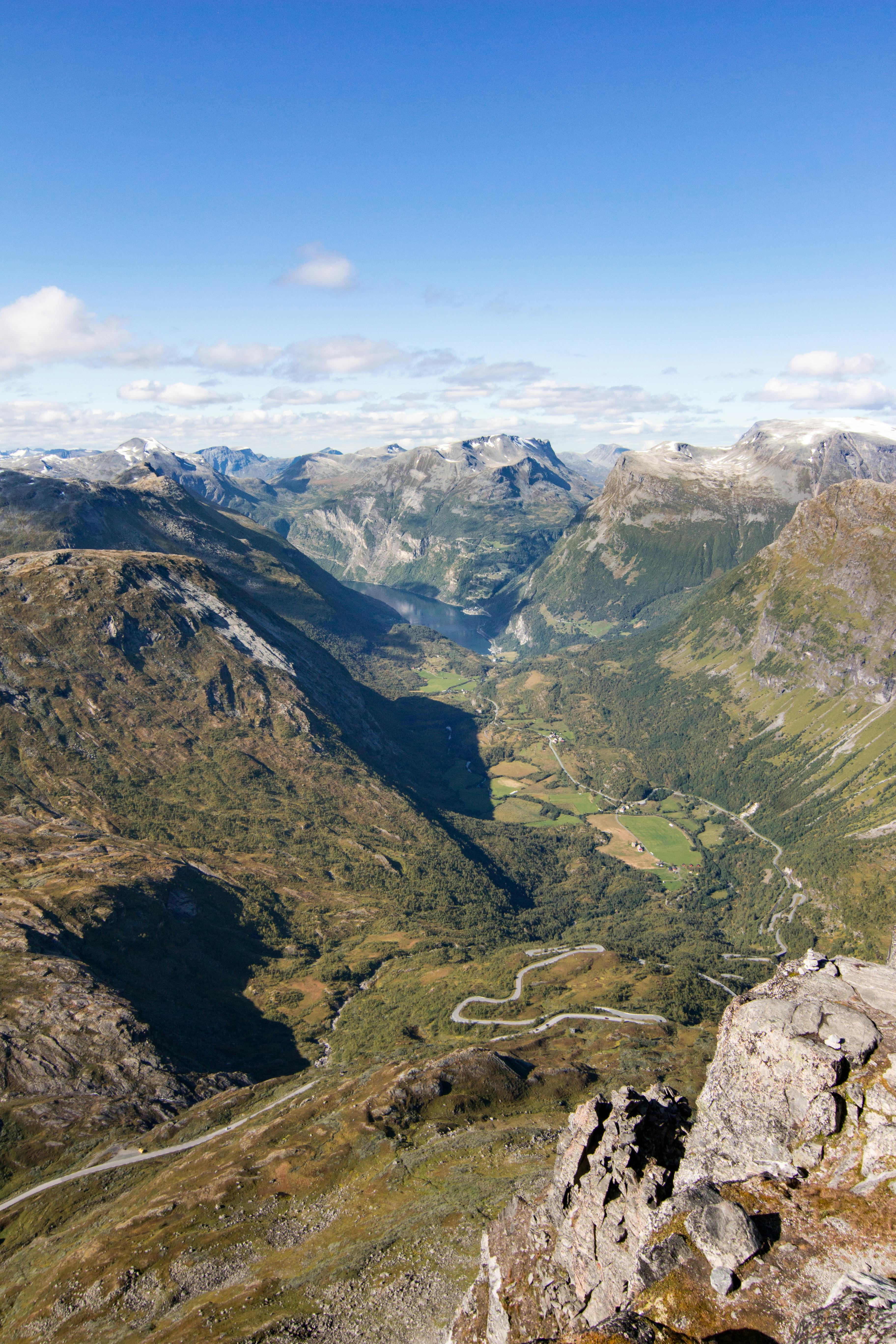 View from Dalsnibba summit at 1,476 meters showing the winding road descending into the Geiranger valley with surrounding mountain peaks