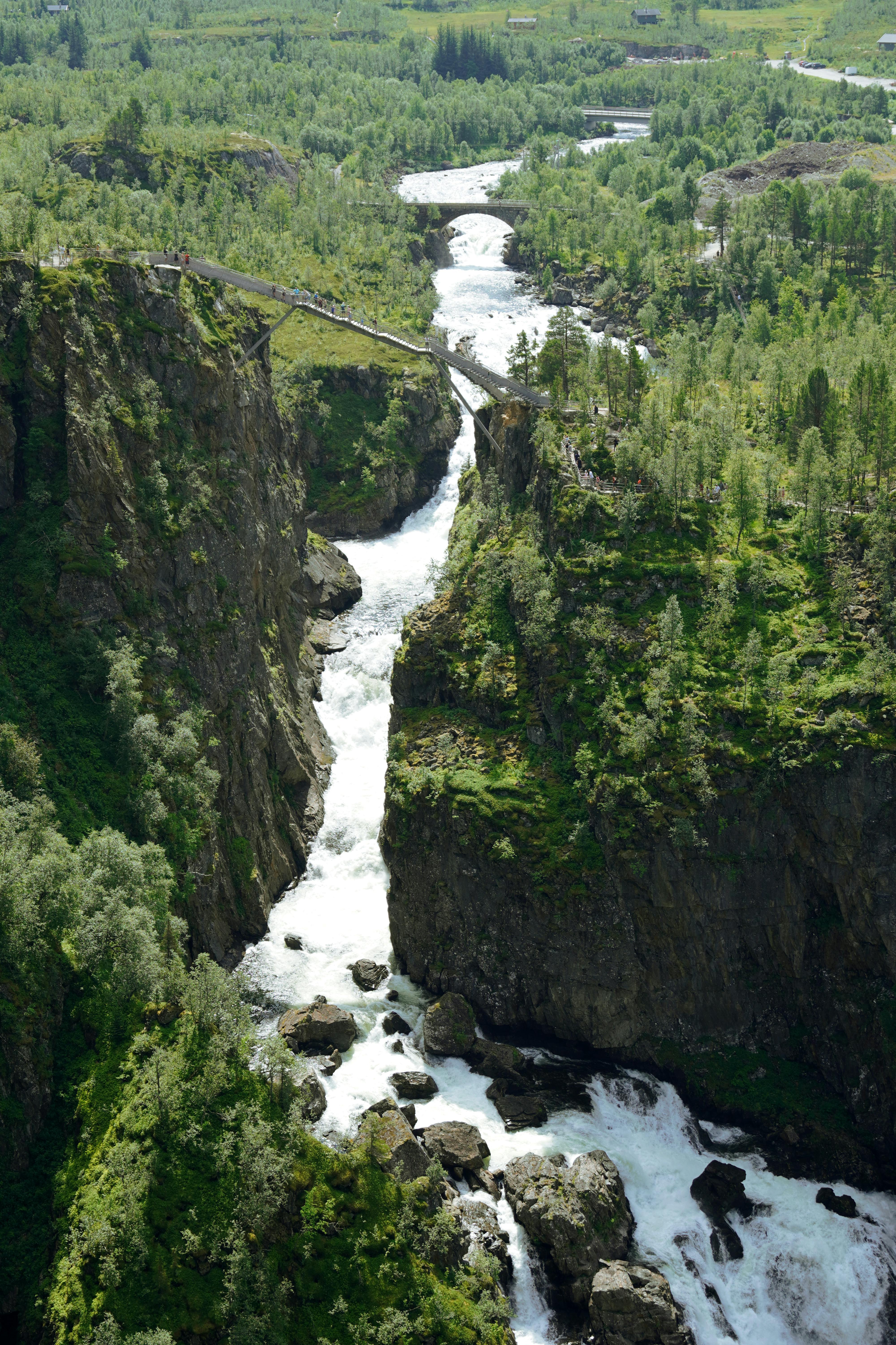 Flydalsjuvet gorge with a powerful waterfall crashing through steep rock walls surrounded by green forest